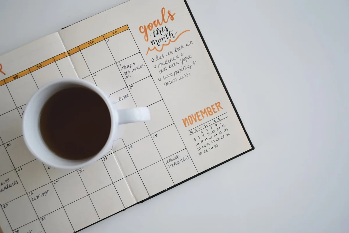 Taza de café sobre una agenda mensual, planificación de los controles de salud